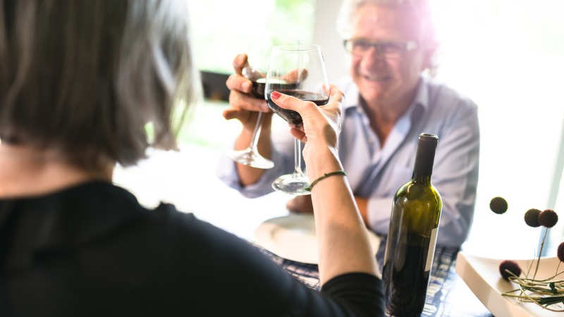 Twee mensen klinken met een glas wijn